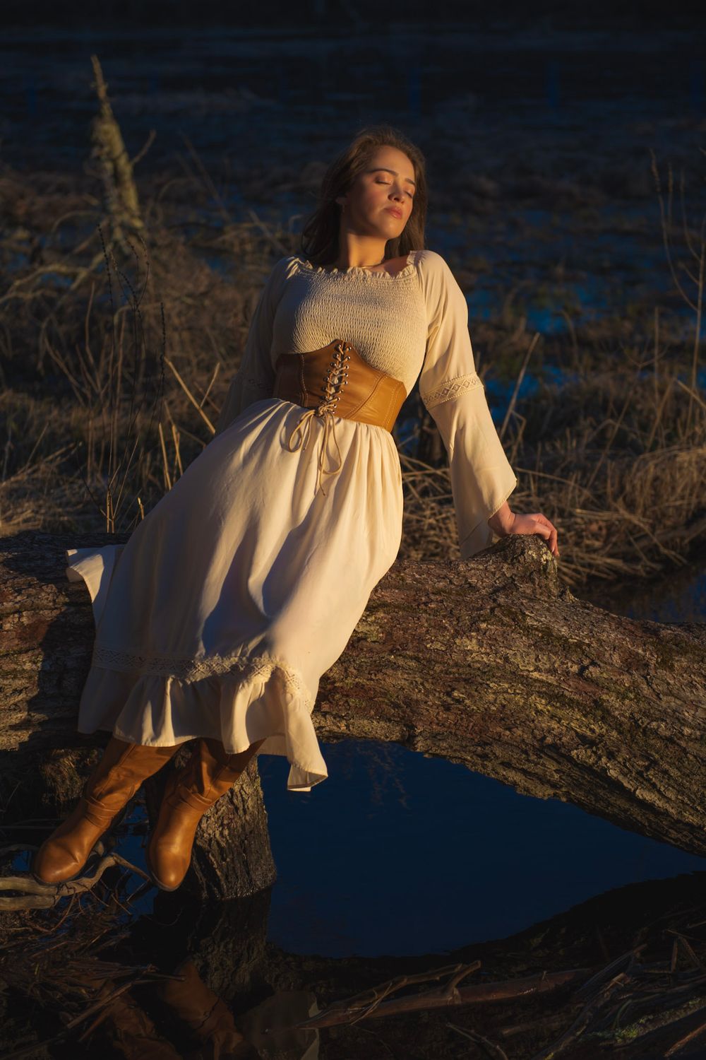 A ethereal white dress flows in golden sunlight as figure poses dramatically against water backdrop.