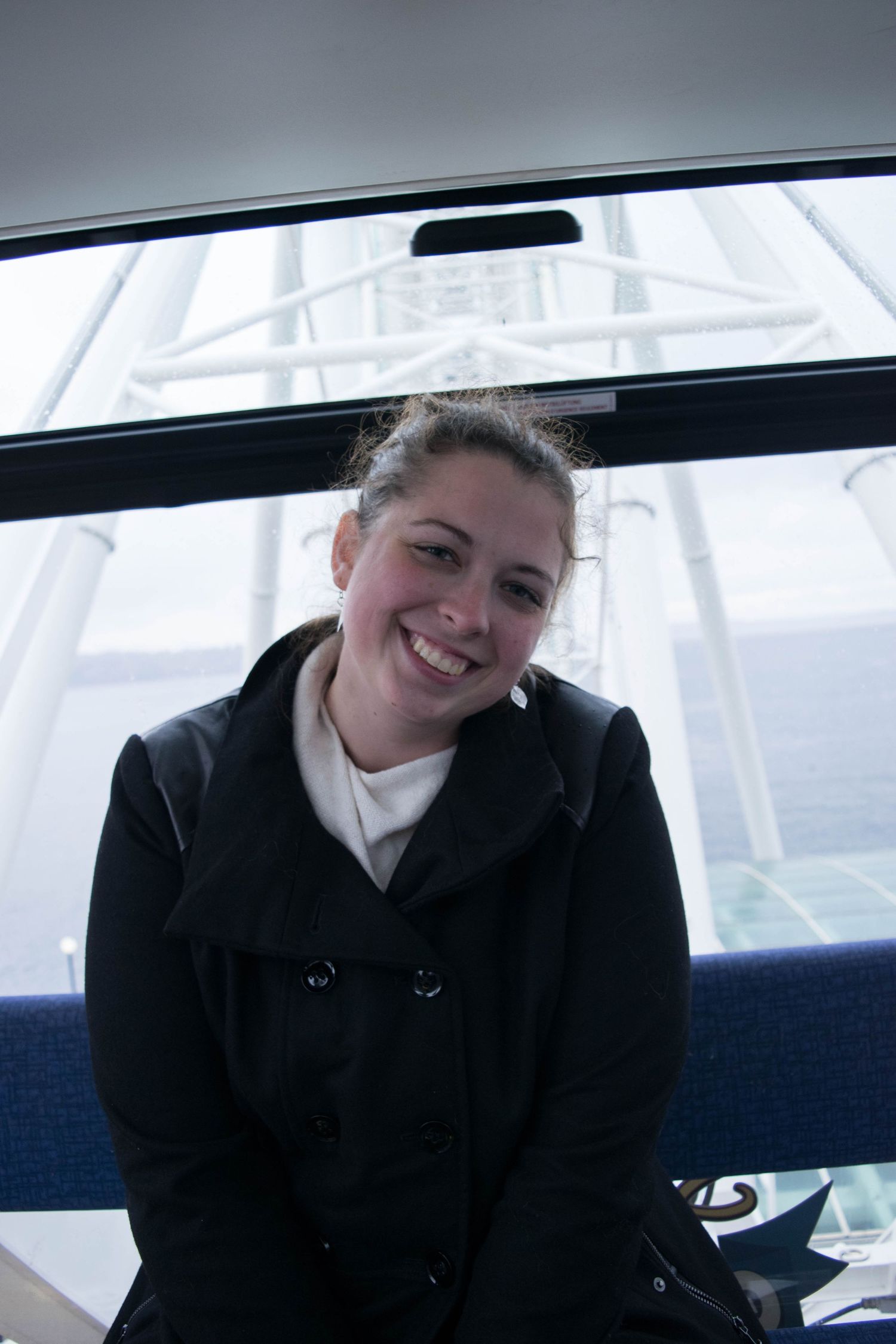Passenger sitting in a ferry cabin with view of the water behind.