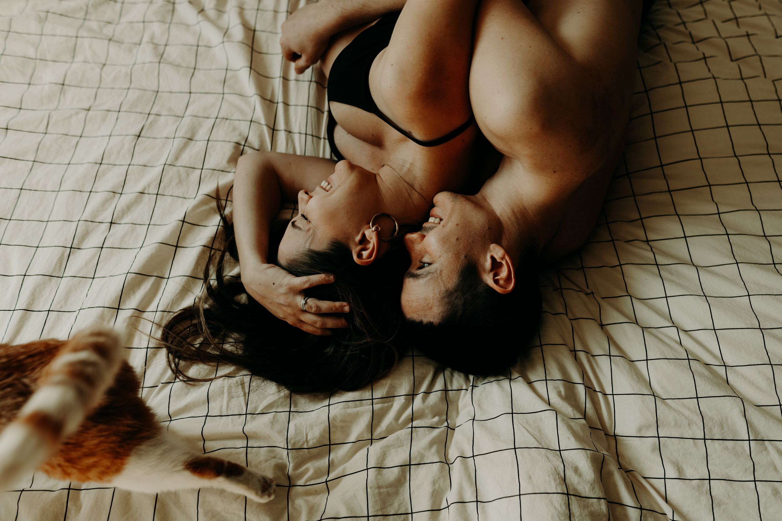Hands gently holding a small baby's feet on a white textured surface in a tender, intimate moment.
