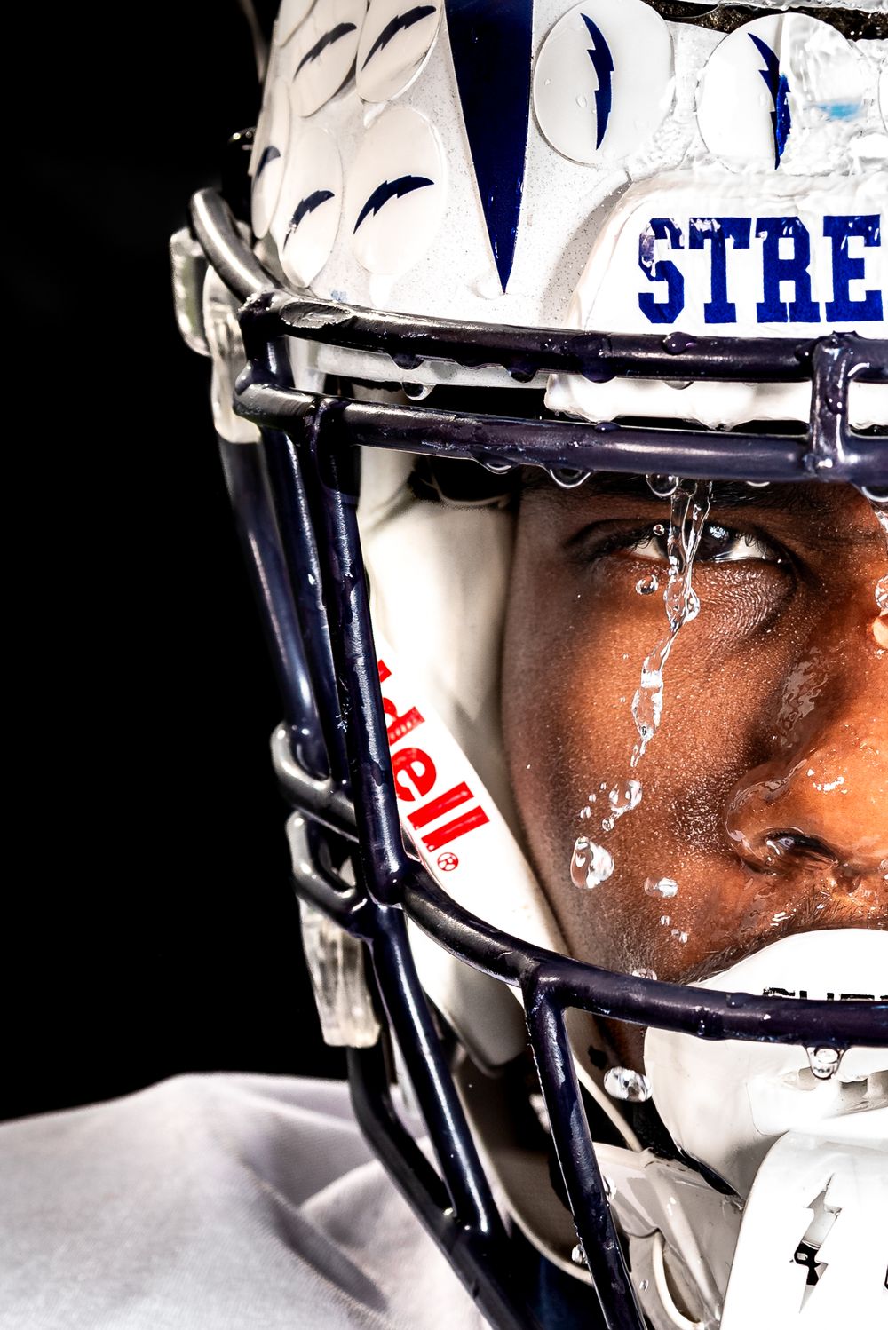 Close up shot of a football player with hemet on and water dripping from it, captured in Sandusky, Oh.