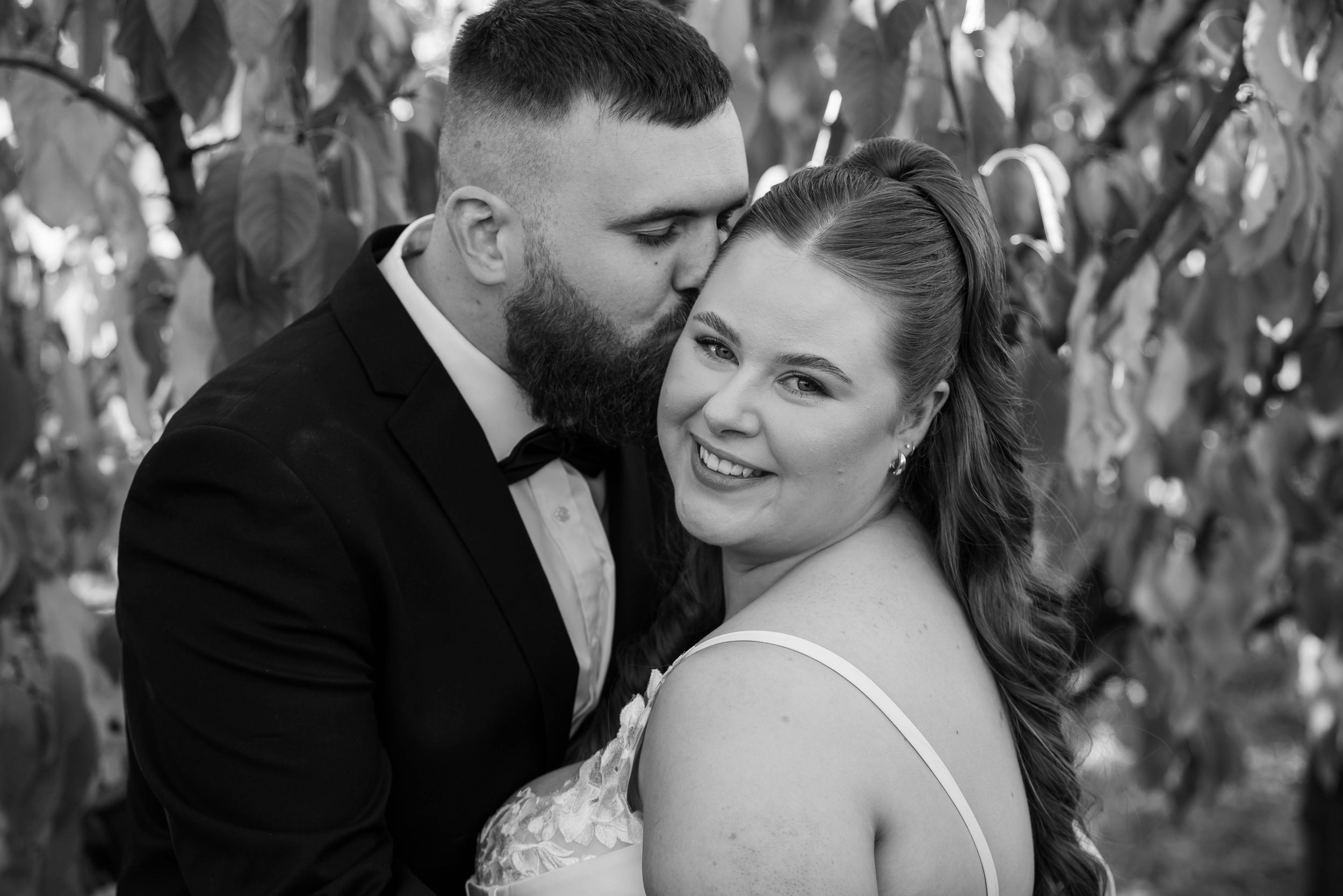 A romantic black and white portrait of a couple sharing intimate moments in a vineyard.