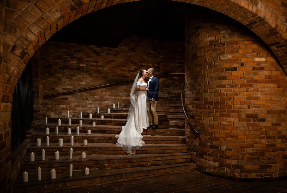Dramatic brick archway tunnel with steps illuminated by natural light.