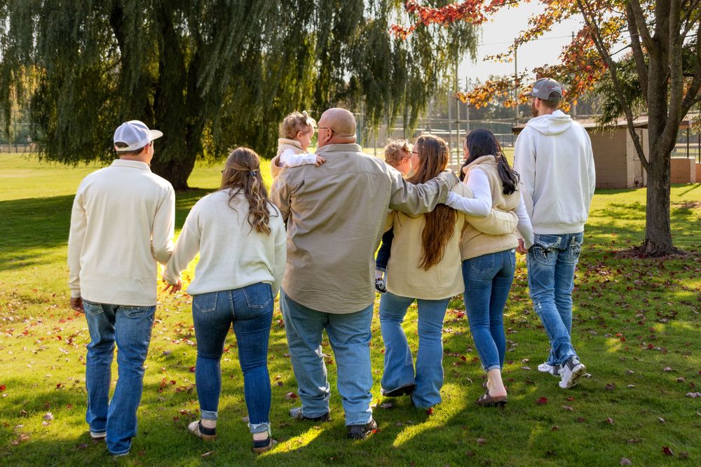Group of people walking together in a line while holding hands in a sunny outdoor park setting.