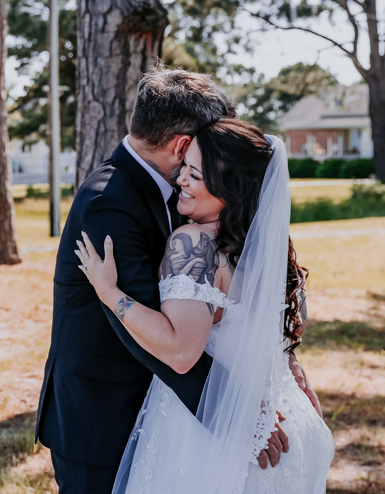 A romantic outdoor wedding photo capturing an intimate embrace between newlyweds against a backdrop of pine trees.