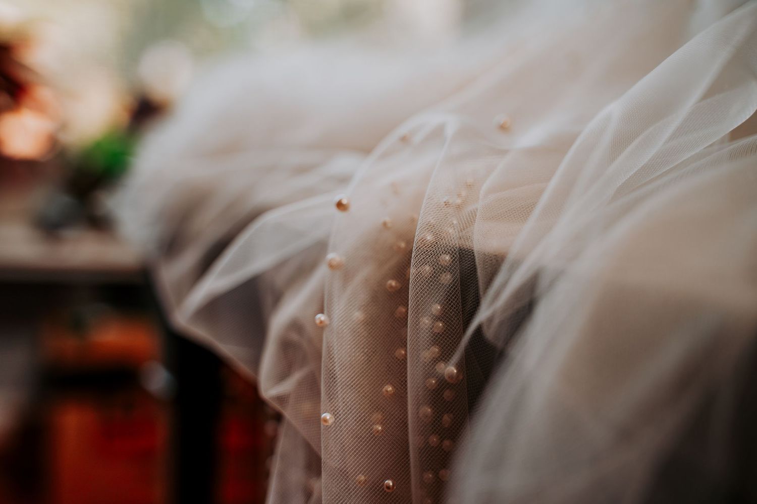 Close-up detailed shot of a wedding veil with delicate pearl beading creating a romantic bridal texture.