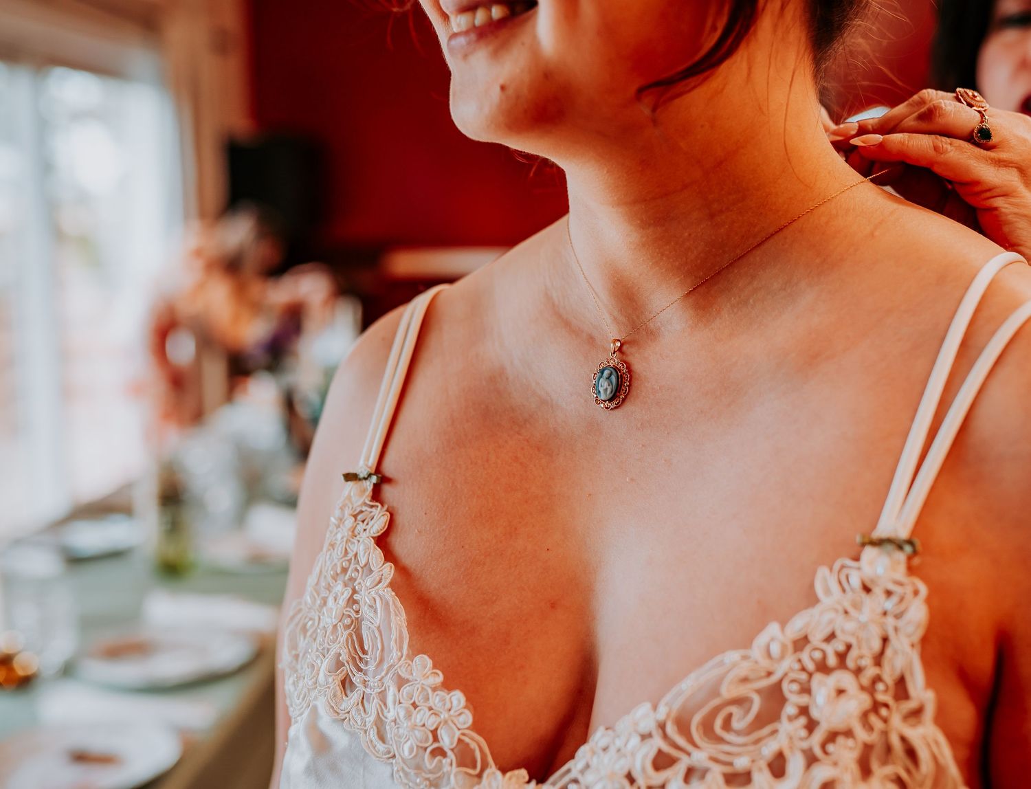 Close-up view of delicate lace details on white straps and bodice of a bridal dress with a necklace pendant.
