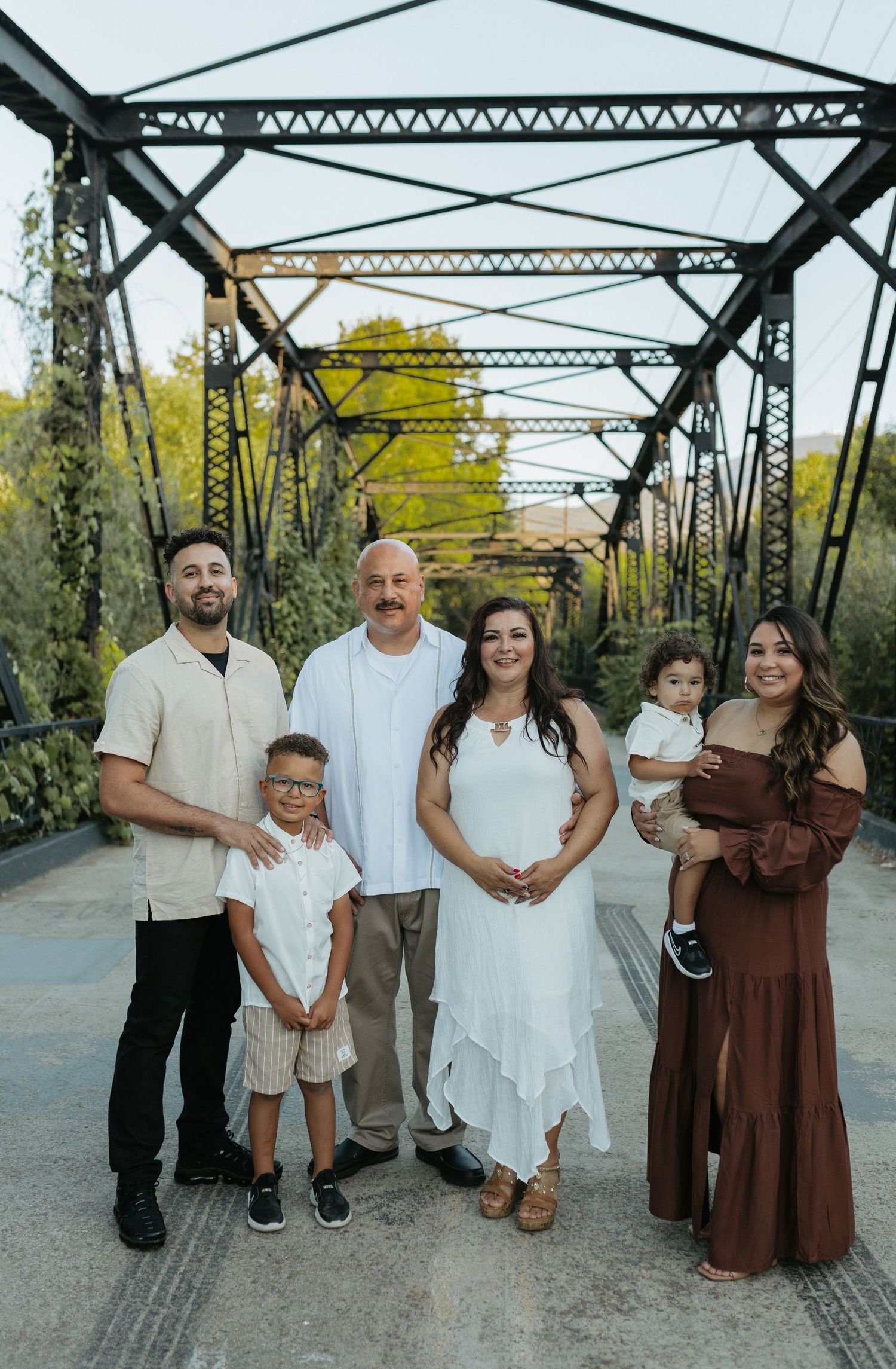 A family of six poses on a leaf covered bridge in San Diego.