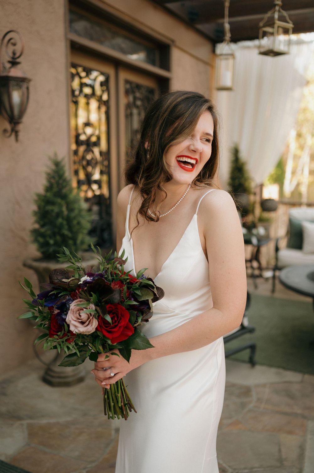 Wedding reception table decorated with red roses, vintage books and burgundy accents.