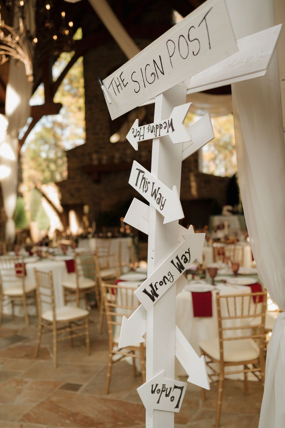 Rustic barn wedding venue decorated with white drapes and elegant table settings.