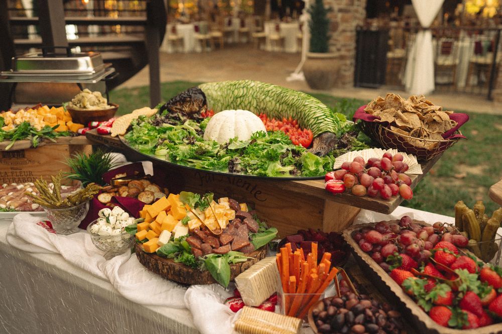 Elegant wedding buffet table with fresh vegetables, fruits and appetizers on display.