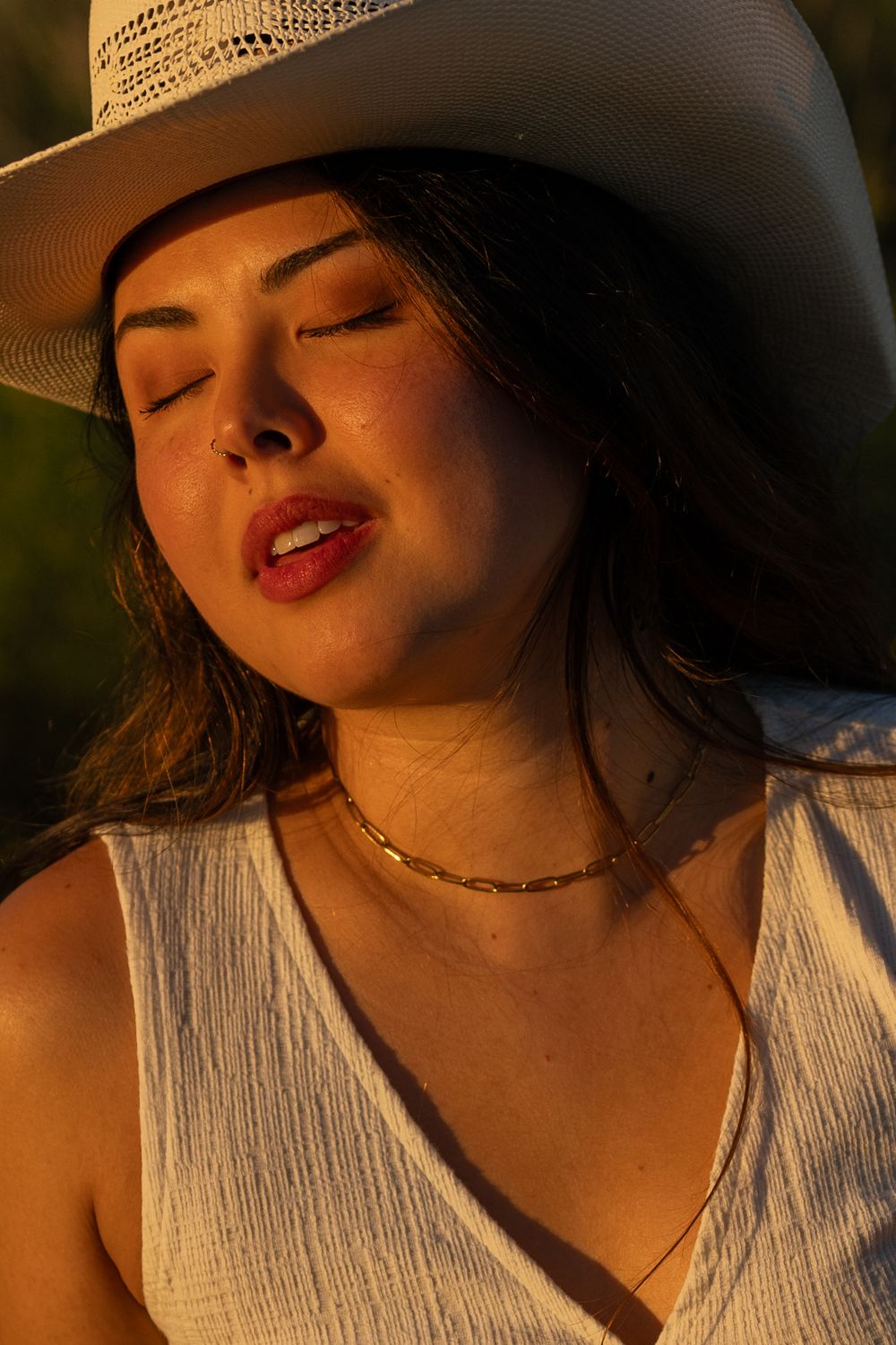 A woman closes her eyes as the setting sun radiates on her face during a creative western cowgirl portrait photoshoot in Fort Worth.