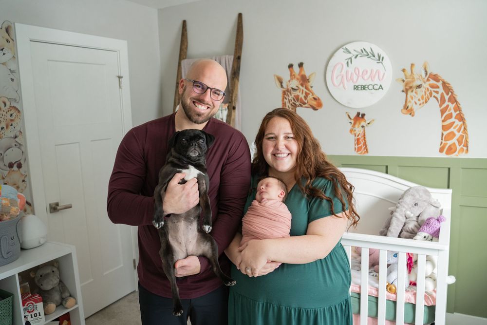 candid in home lifestyle photo shoot of family with newborn baby in their nursery with their dog. Clean safari animal theme nursery.