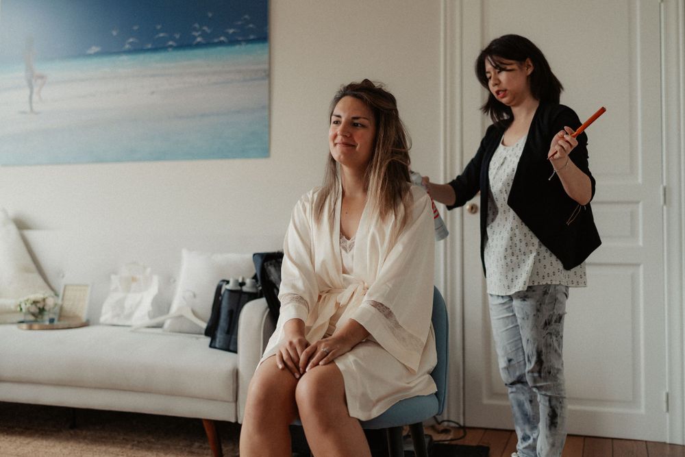 Two people getting ready in a room with a beach artwork on the wall.