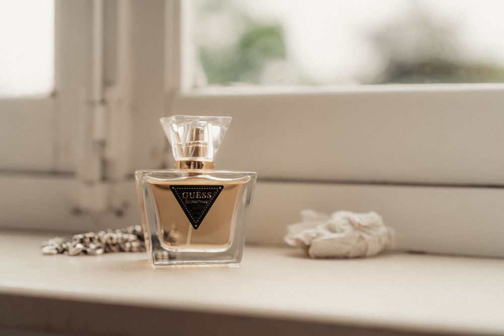 Elegant perfume bottle displayed on a white windowsill with soft natural lighting.