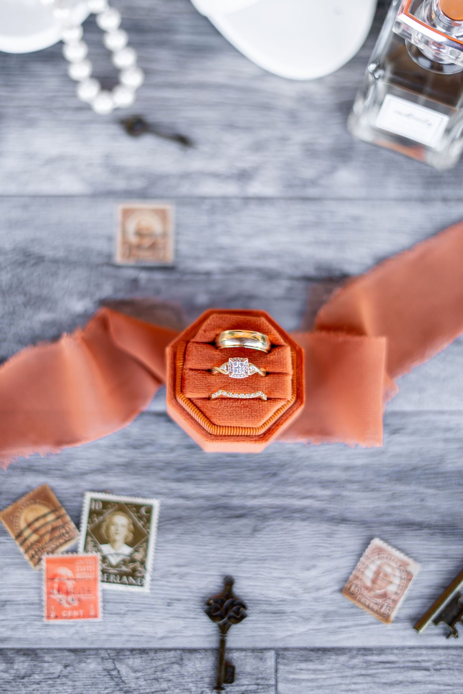 Engagement ring in coral velvet box surrounded by vintage stamps and decorative elements.