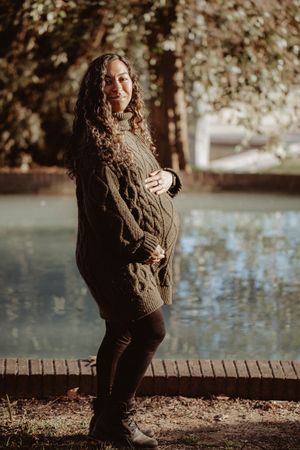 Cozy autumn portrait session by a lake with warm knit sweater and natural lighting.