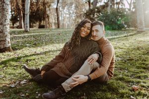 Couple sitting together on grass in sunlit park setting.