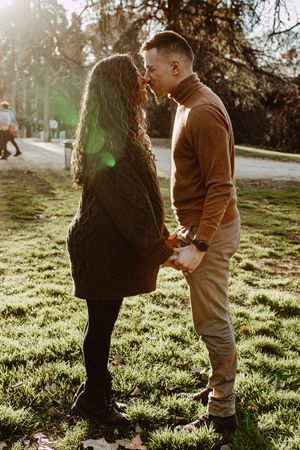 Candid outdoor maternity session in a sunlit park with golden hour lighting.