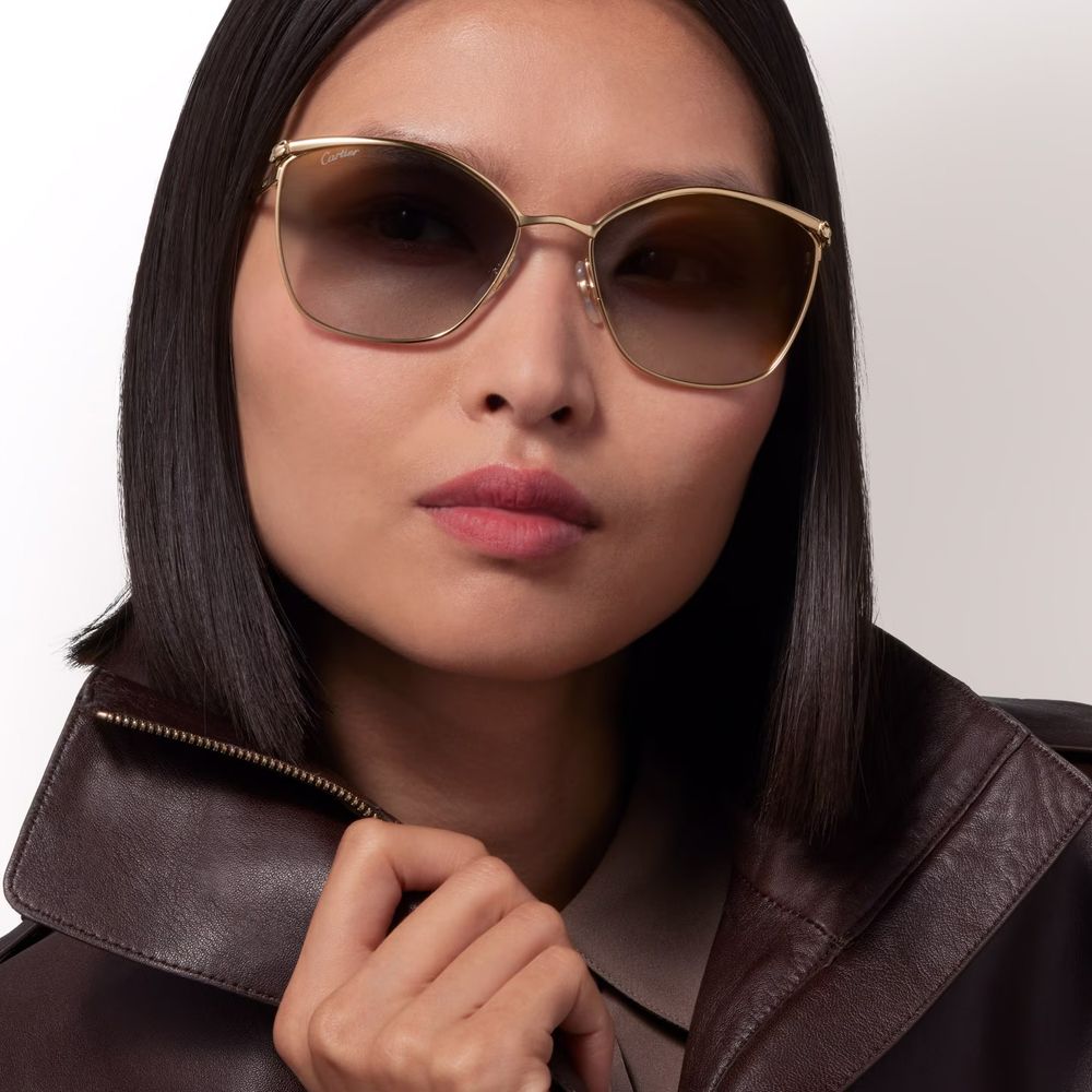 Fashion model wearing stylish sunglasses in a black leather jacket poses for a glamorous portrait series.