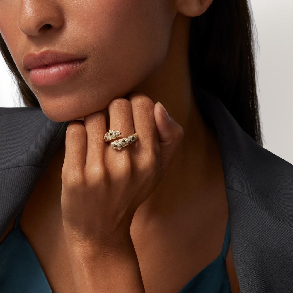 Close-up view of a hand wearing a gold and pearl cluster ring against a dark blazer.