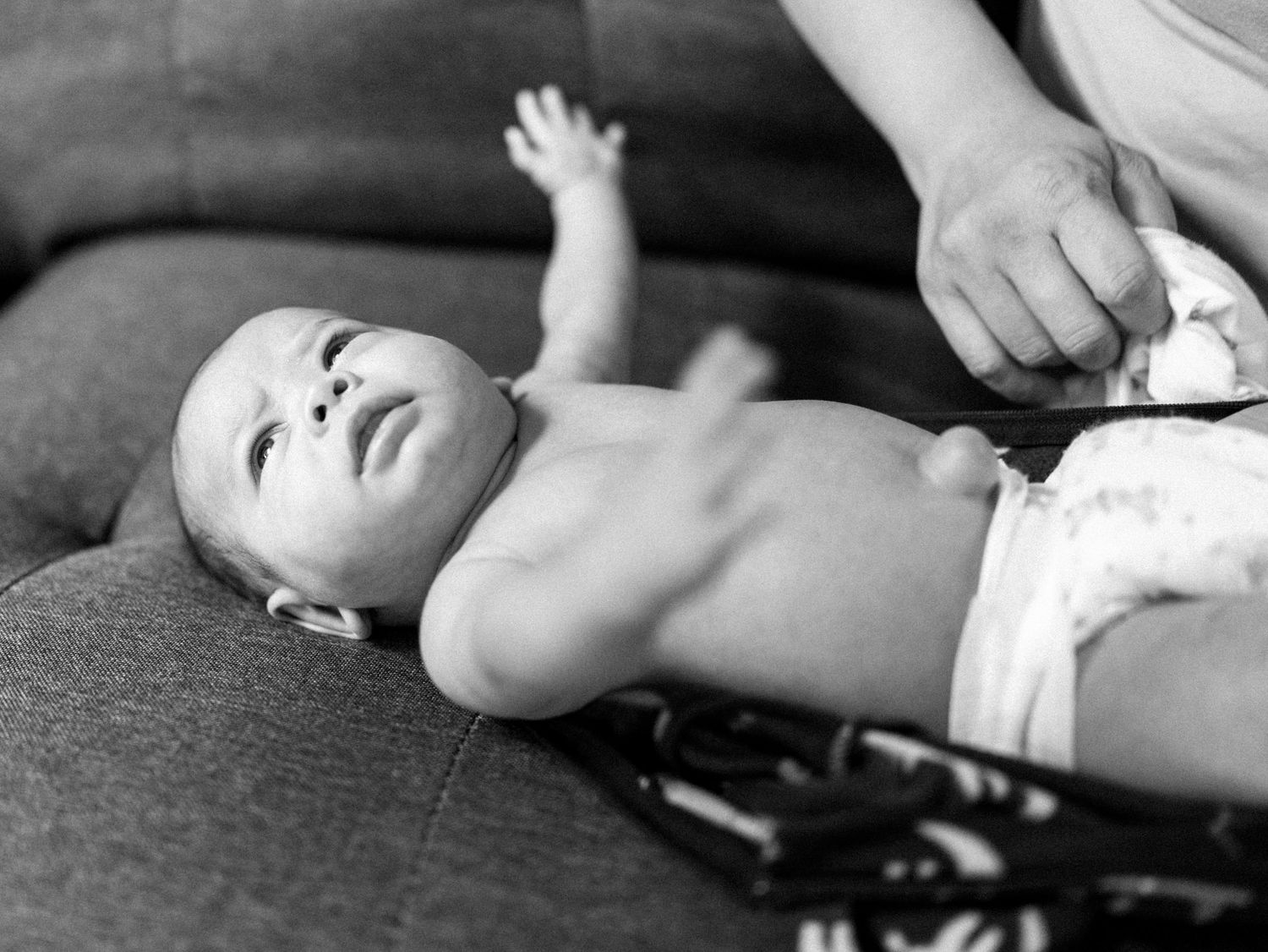 Baby lies on dark gray surface while being photographed from different angles.