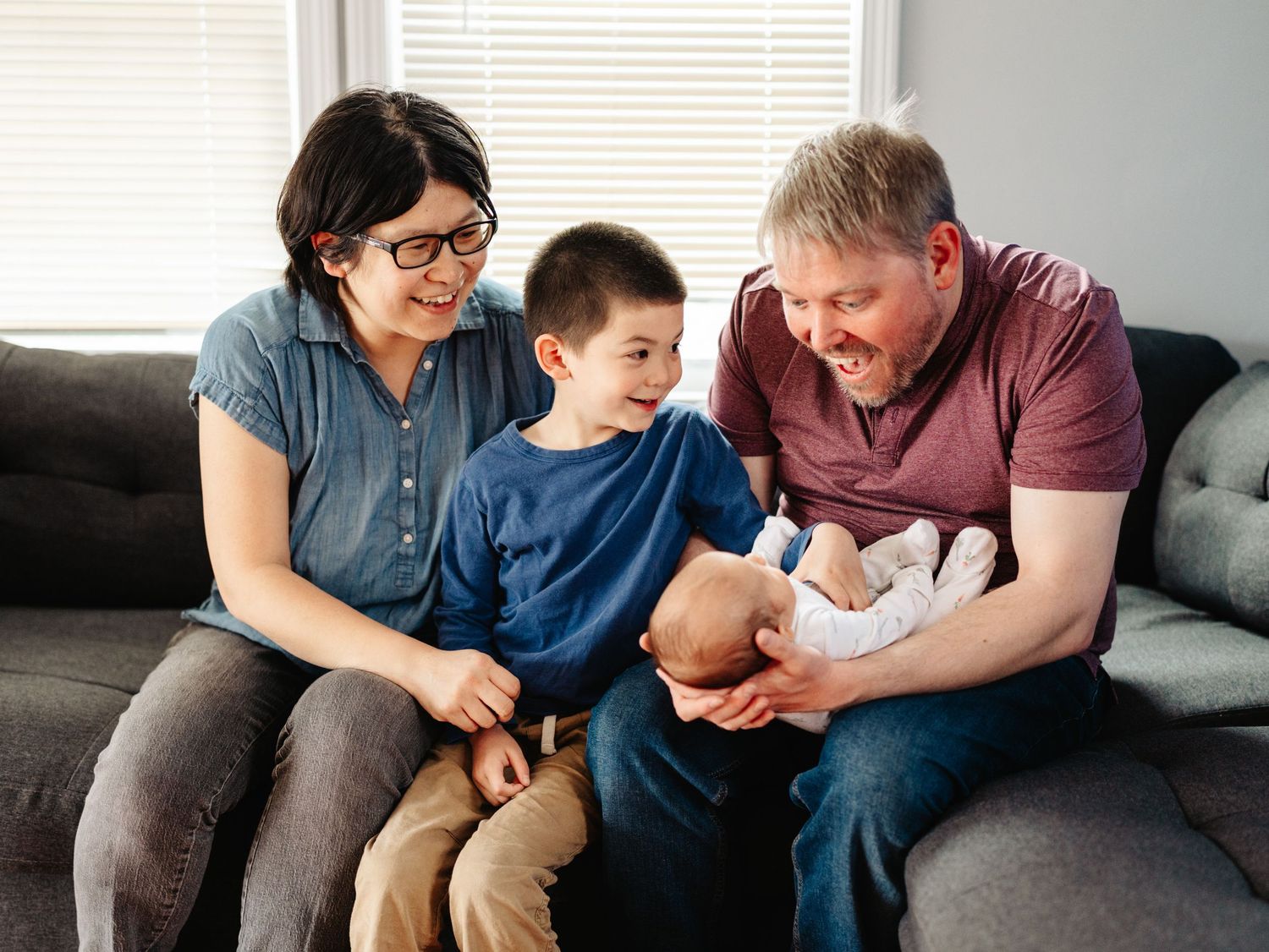 Family members sitting together on couch bonding with infant.