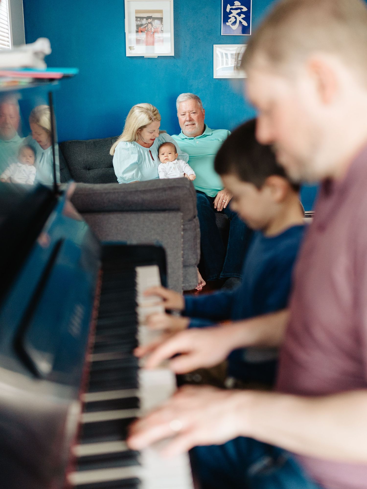 Family gathering in room with bright blue walls and piano.