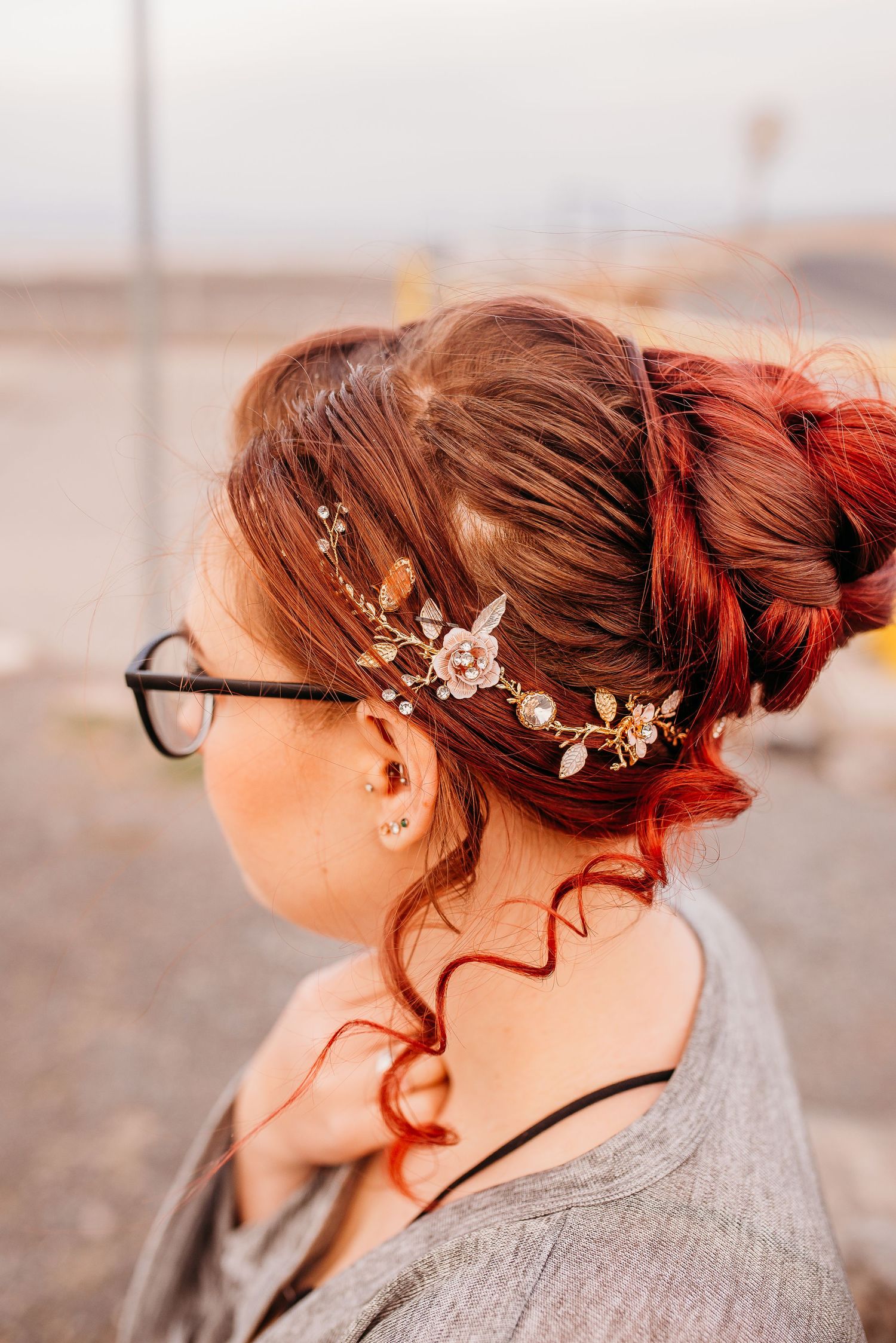 Delicate floral hair accessory adorning red hair styled in an updo with glasses.