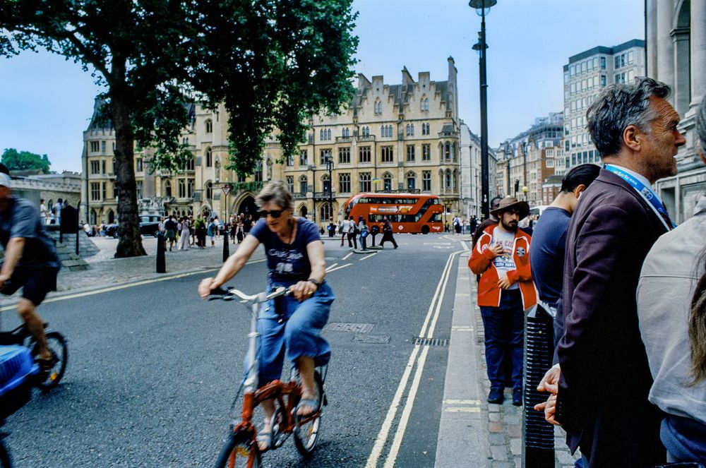 Busy street scene in London with cyclists and pedestrians near historic buildings.