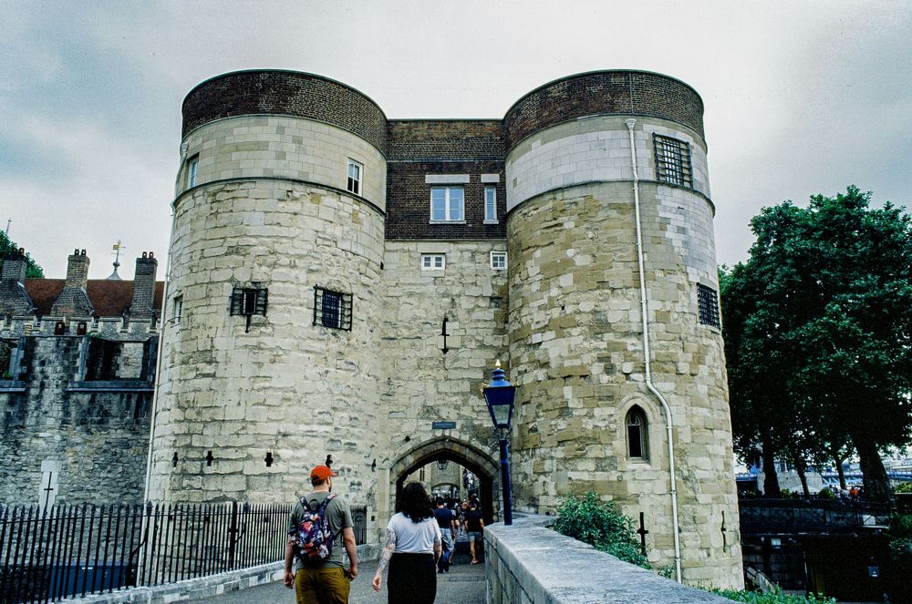 Medieval stone gatehouse with circular towers at the entrance to the Tower of London.