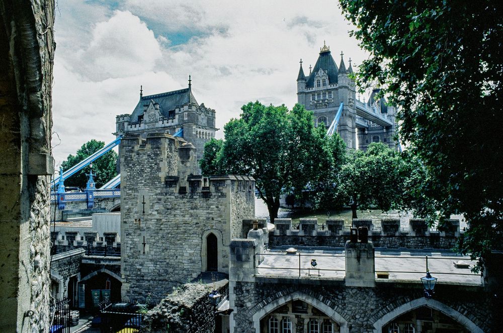 Historic Tower of London fortress with Tower Bridge visible in background.