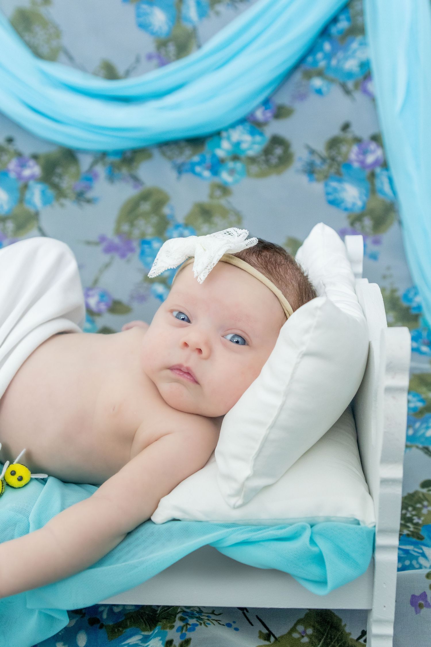 East Texas newborn photographer captures a baby wrapped in pastel tones with a delicate headband