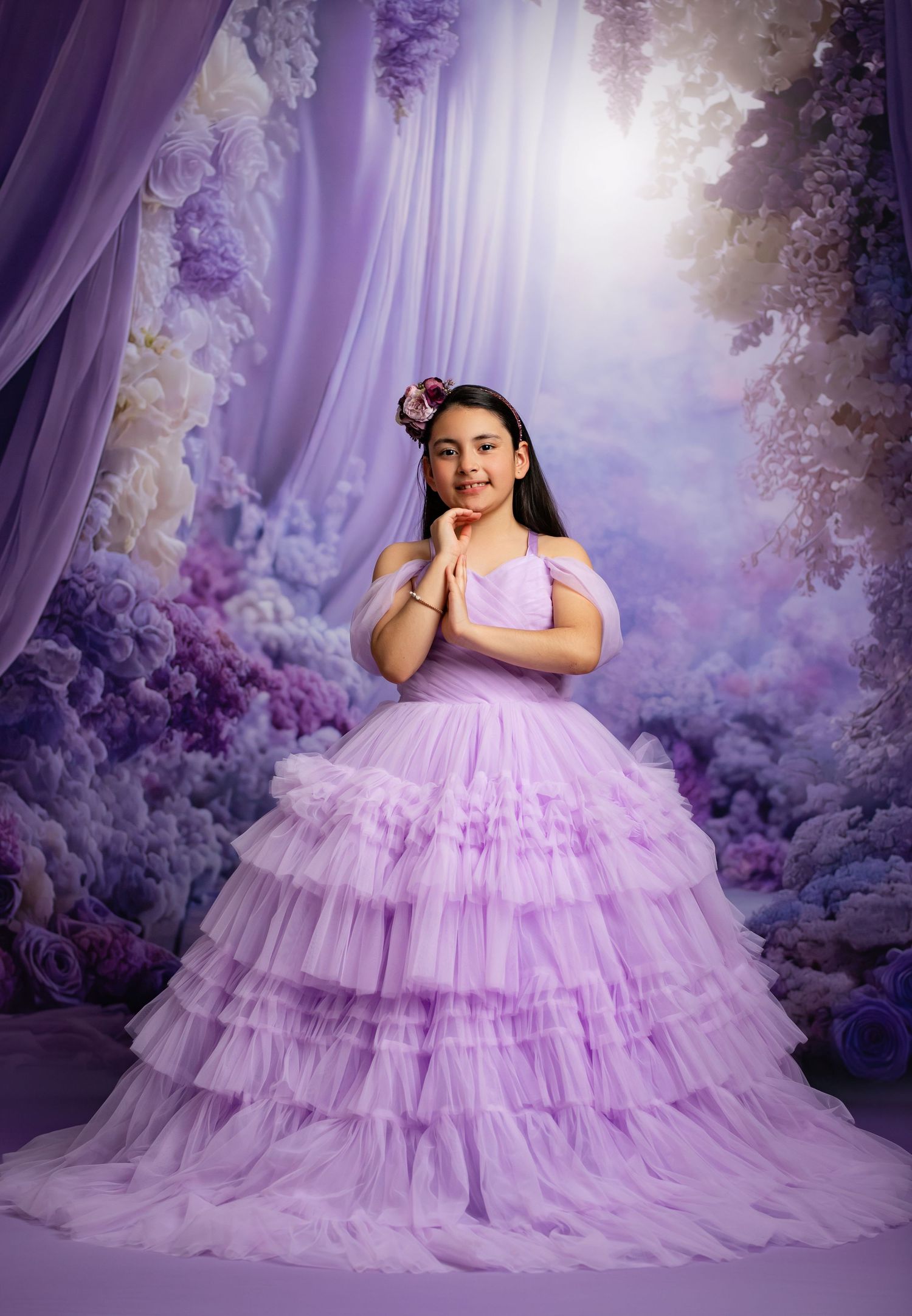 Dramatic purple ball gown photographed against a swirling sunset sky with ethereal flowing fabric.