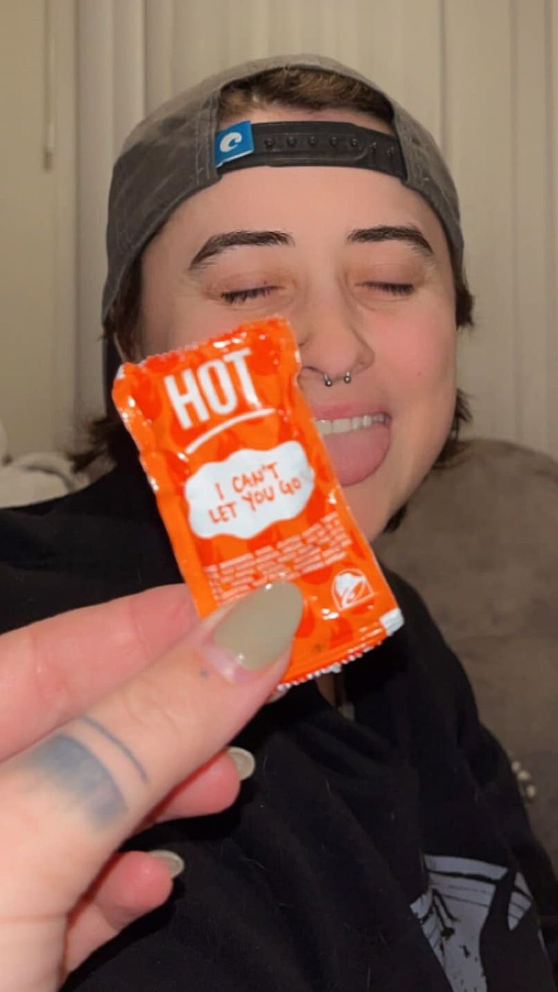 Close-up shot of someone holding an orange Taco Bell sauce packet.