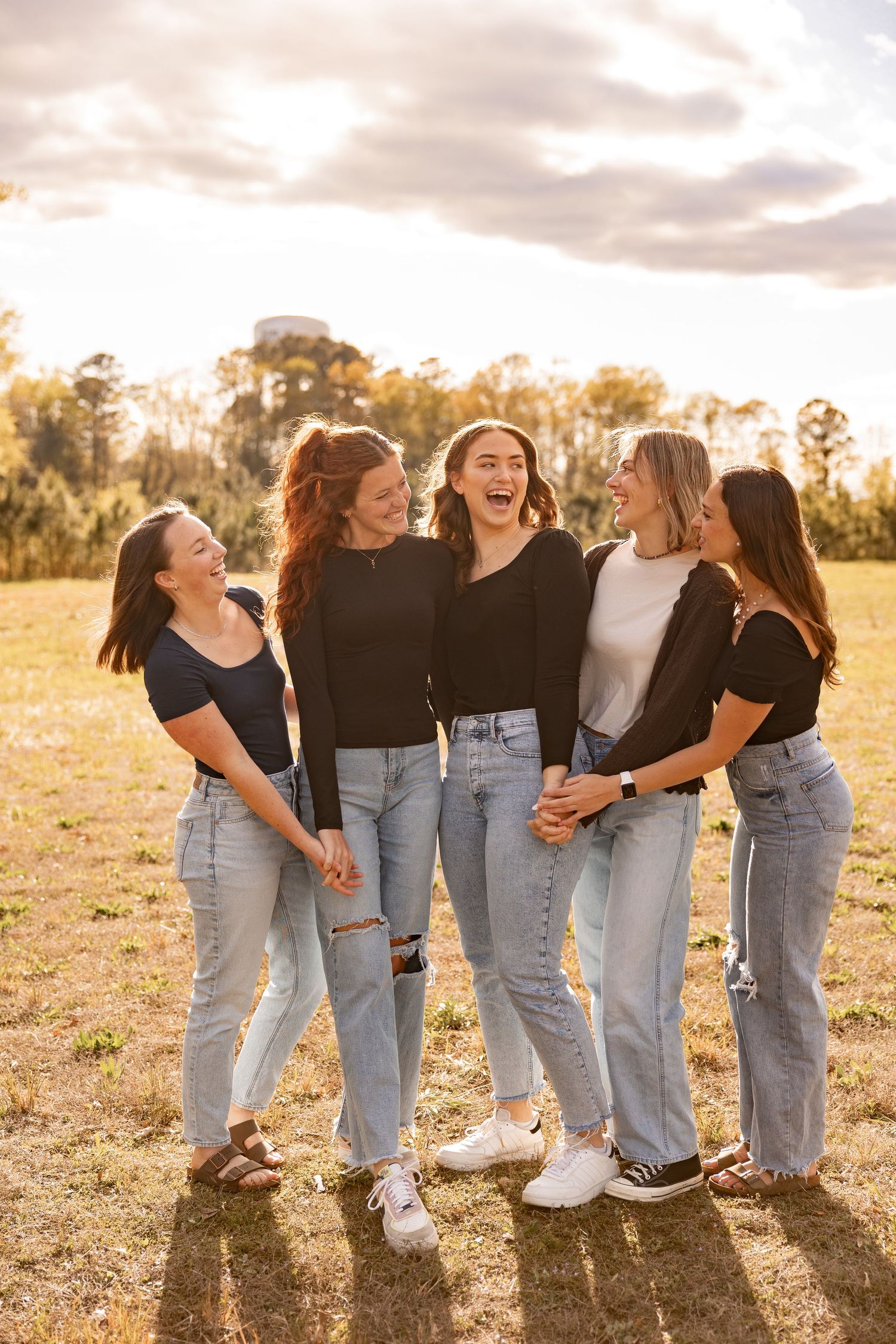 Group of friends laughing and smiling with one another at sunset