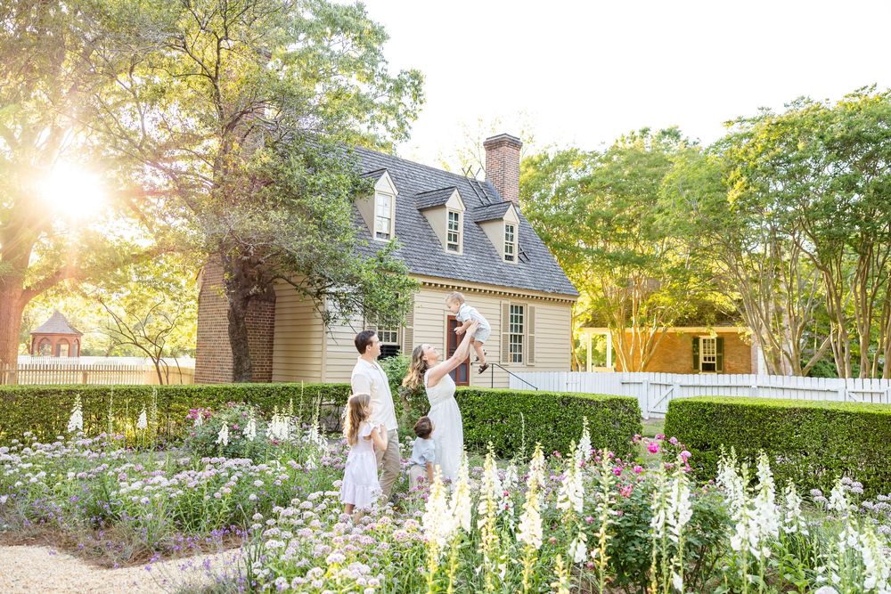 Family portrait in a cottage garden in Colonial Williamsburg amongst the foxglove and roses with glowing light illuminating the landscape.
