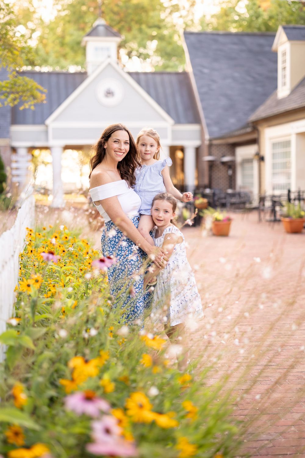 Photograph of mother and daughters posing behind florals in historic Yorktown, Virginia. Yorktown Virginia family photography is very scenic