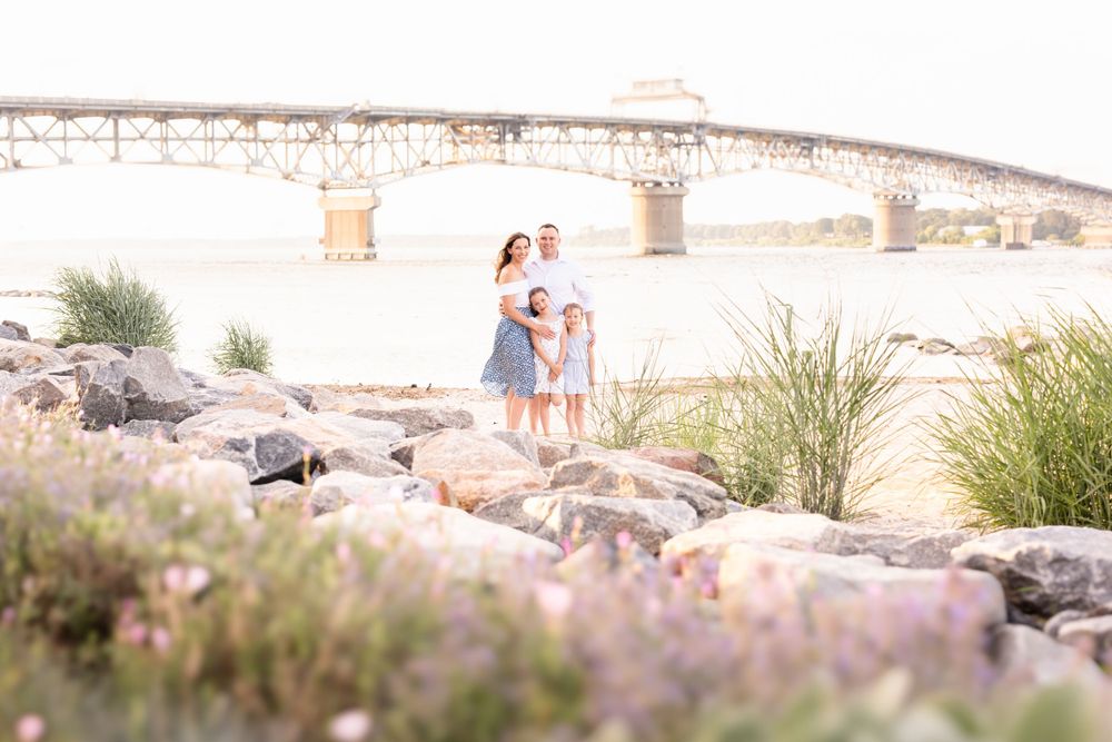 Photograph of family posing during vacation in front of bridge at historic Yorktown Beach