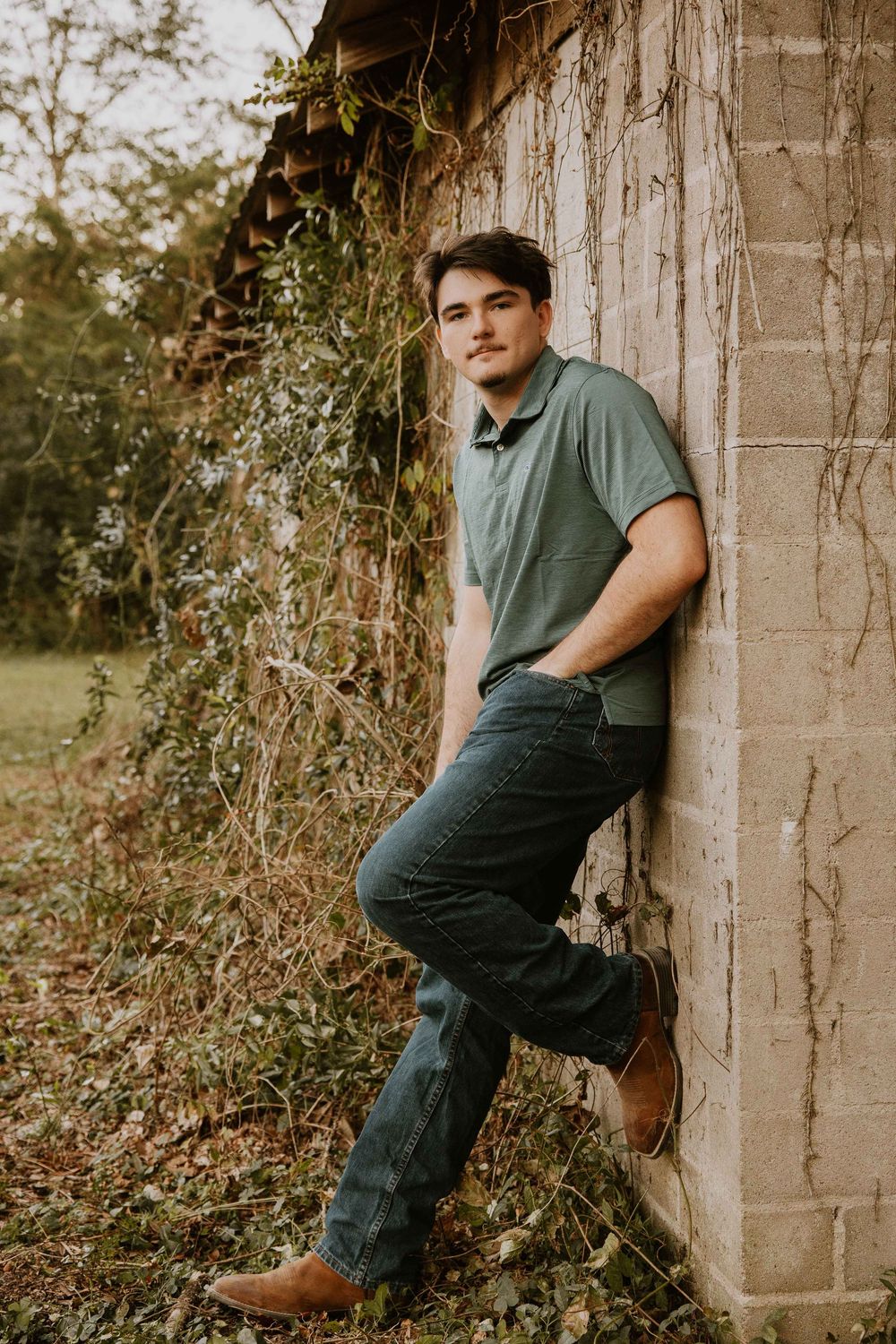 Someone poses casually against a concrete wall during a golden hour photoshoot.