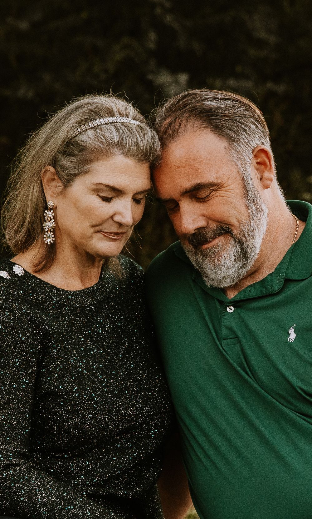 A couple in black and green outfits share an intimate moment during their photoshoot.