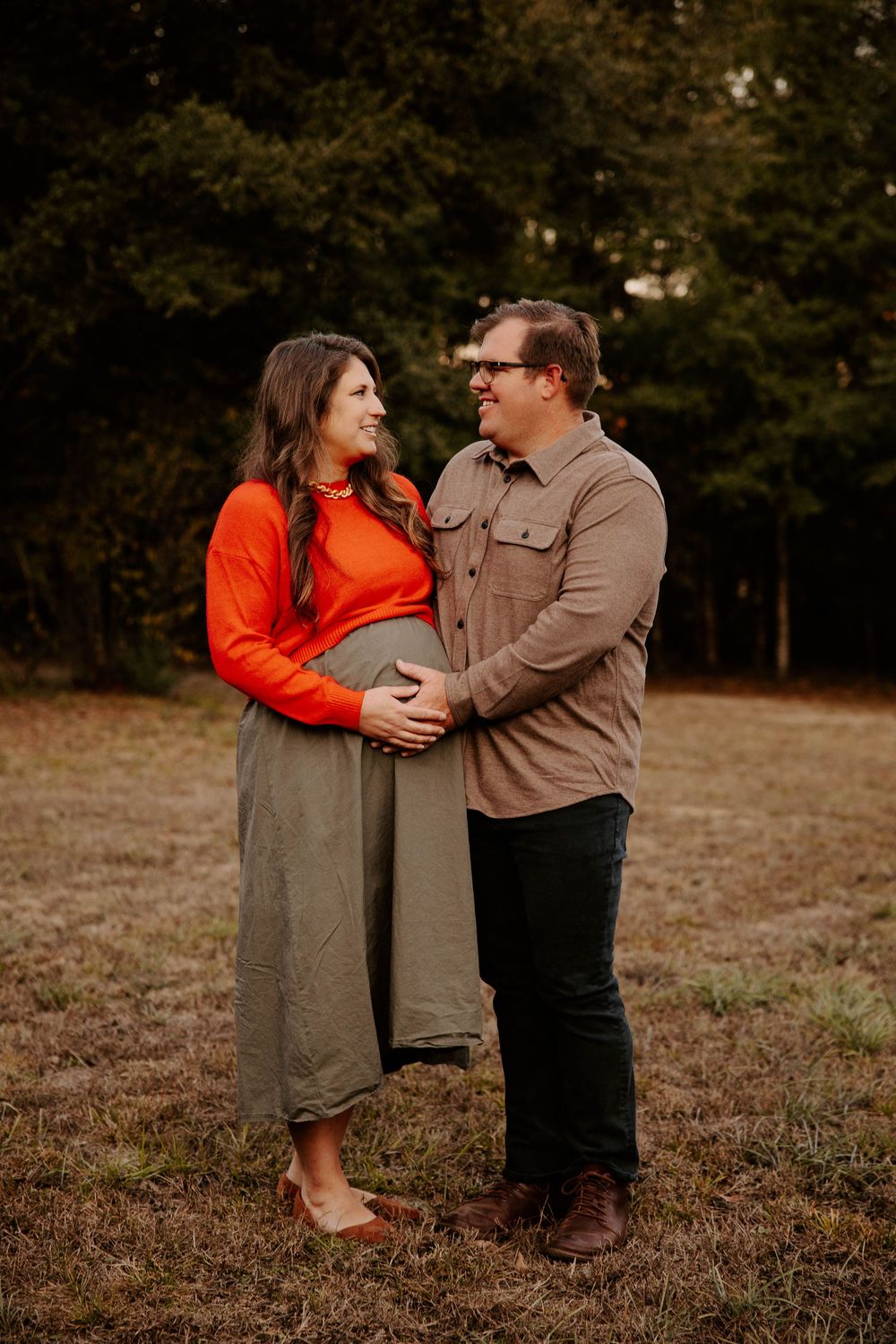 Couple in casual fall attire sharing tender moments in outdoor field setting.