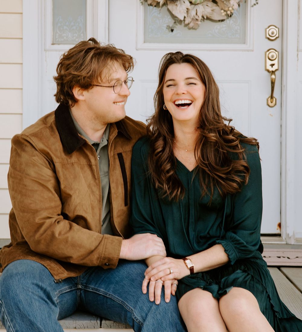 Couple sitting on white porch steps laughing and enjoying each other's company.