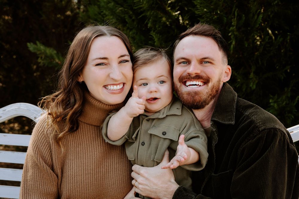 Young family shares joyful moments with baby during outdoor autumn photoshoot.