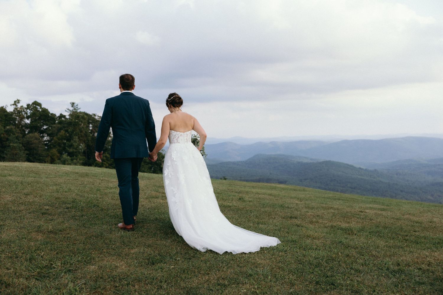 A couple stands on a hilltop overlooking a misty mountain landscape. Luxury Estate Wedding Photographer in NC
