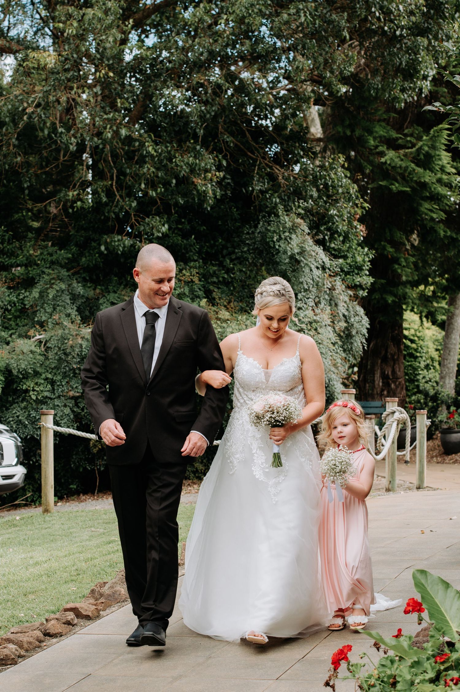 A formal procession down a garden path during a wedding ceremony.