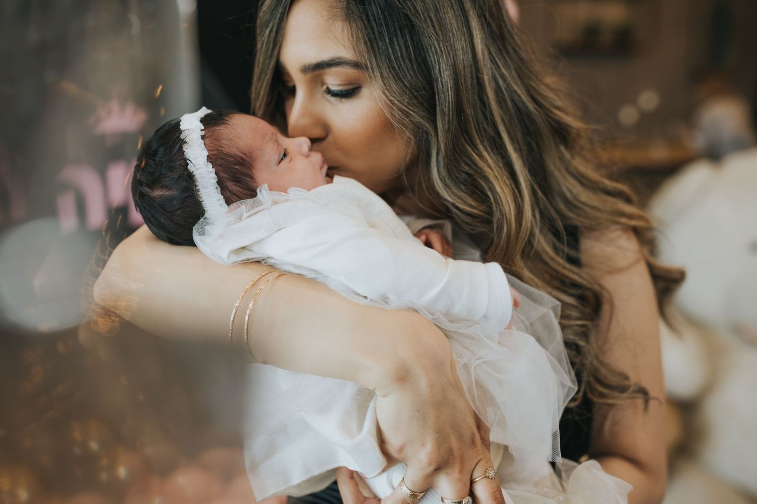 Tender moment between mother and newborn baby in soft lighting.