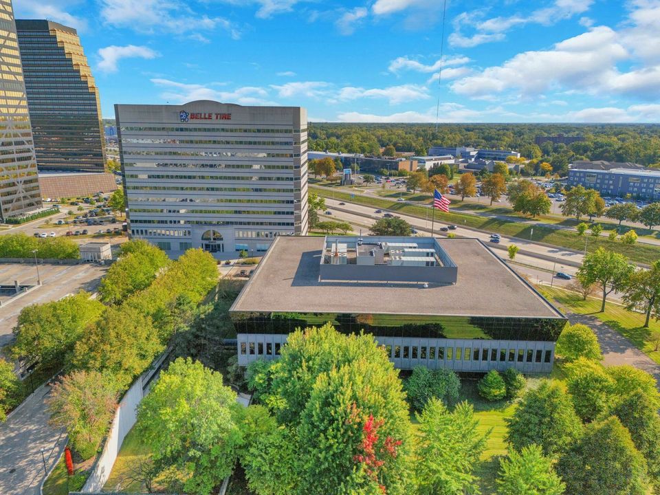 Aerial view of urban office complex with Belle Tire tower surrounded by trees and city infrastructure.