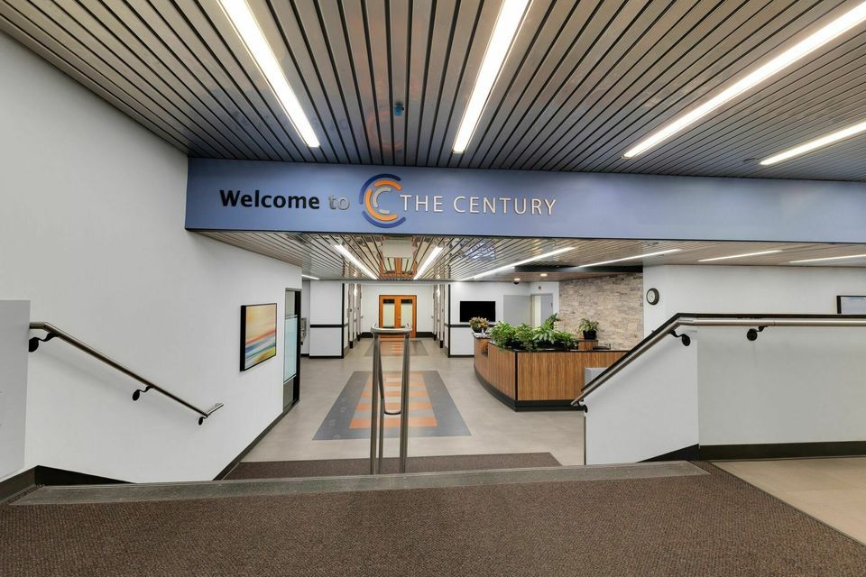 Welcome to The Century building entrance with modern signage, staircase, and bright overhead lighting.