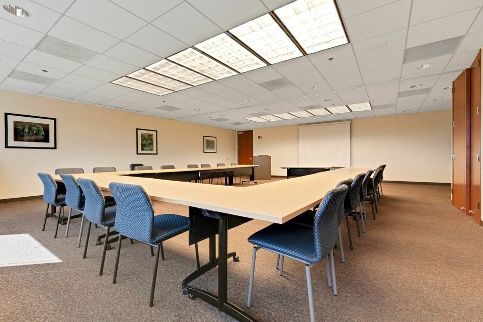 U-shaped conference room with blue chairs and wooden tables under bright skylights.