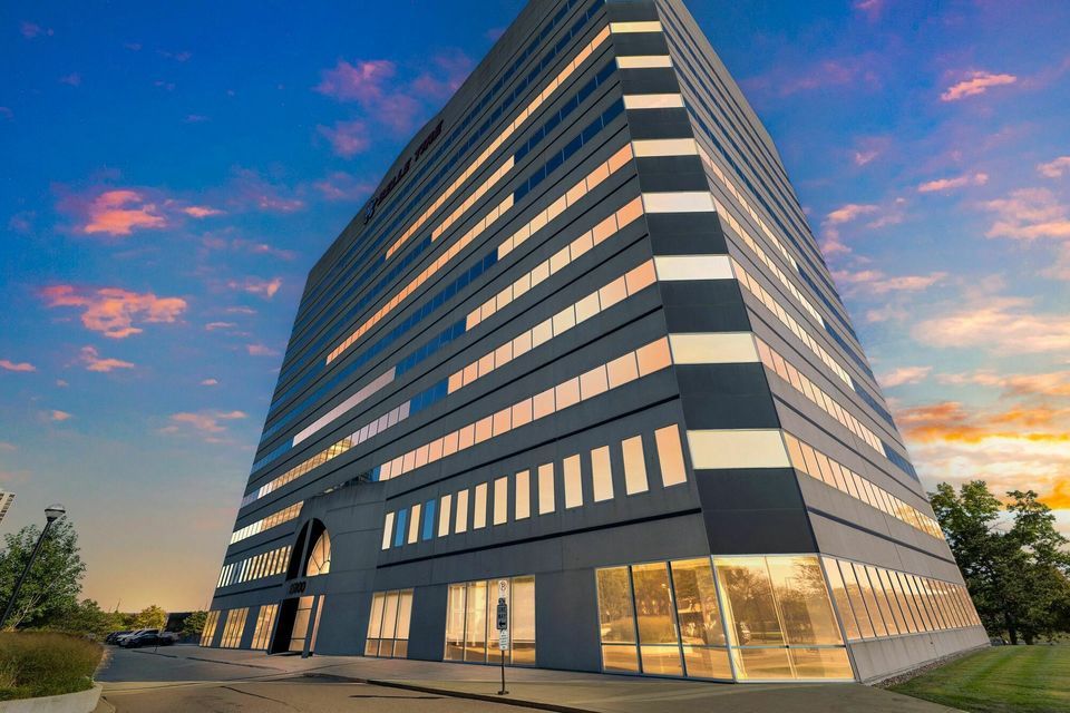Modern multi-story office building with sleek glass and steel exterior illuminated at dusk.